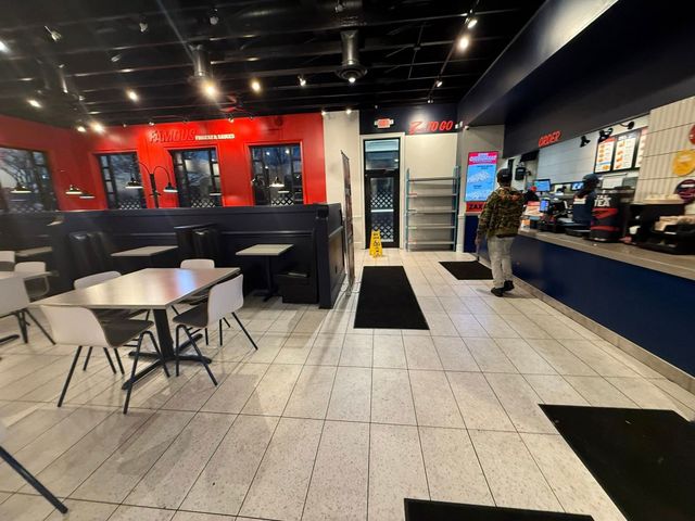 Modern cafe interior with red walls, tables, stools, and a person standing near the counter