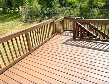 Wooden deck with railings overlooking a grassy yard and trees