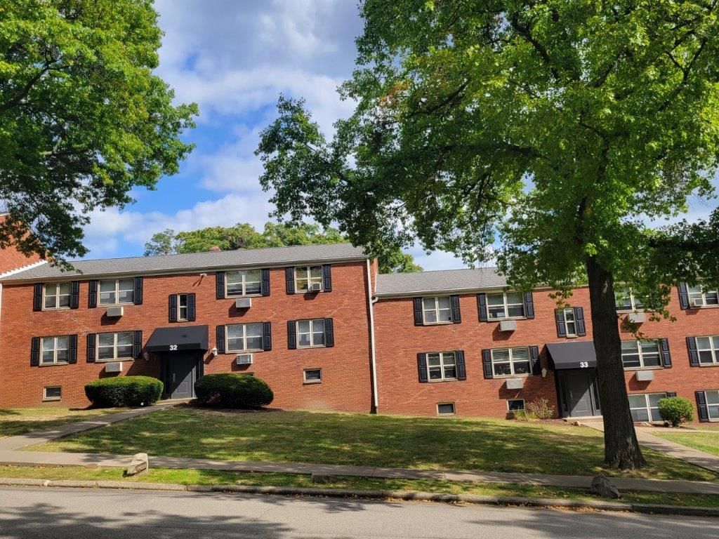 A brick apartment building with a tree in front of it