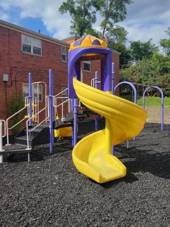 A yellow and purple playground with a yellow spiral slide