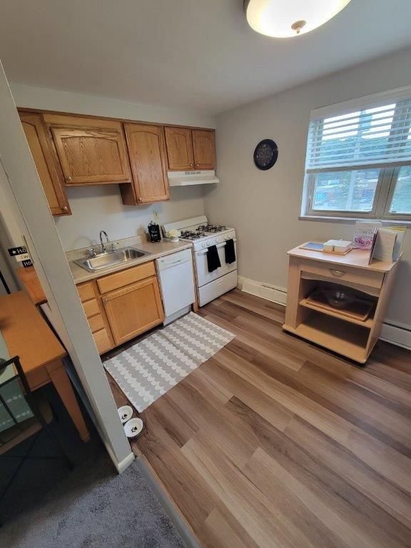 A kitchen with wooden cabinets , a stove , a sink , and a window.