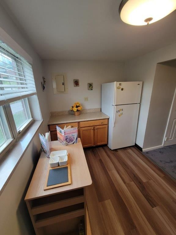 A kitchen with a table , refrigerator , cabinets and a window.