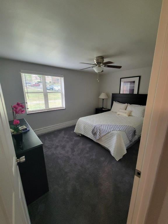 A bedroom with a bed , dresser , and ceiling fan.