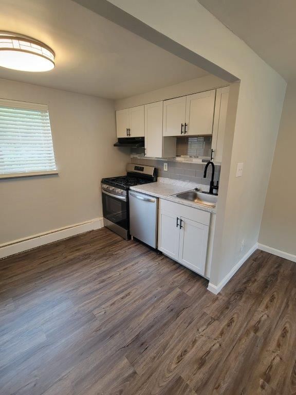 A kitchen with a stove , dishwasher , sink and cabinets.