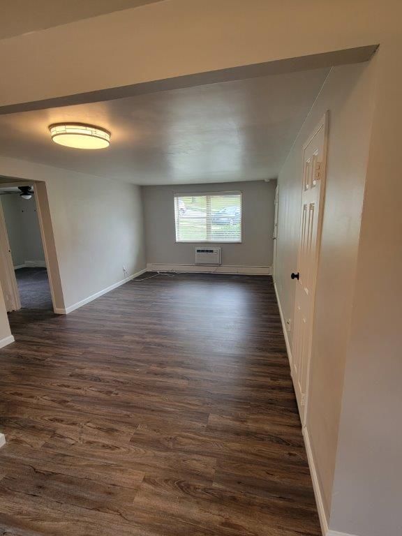 An empty living room with hardwood floors and a window.