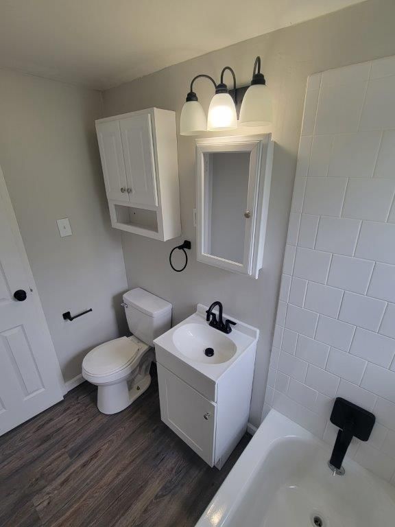 A bathroom with a toilet , sink , mirror and bathtub.