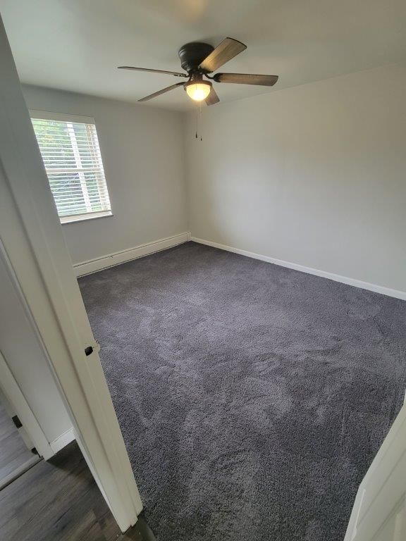A bedroom with a ceiling fan and a window.