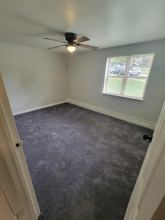 An empty bedroom with a ceiling fan and a window.