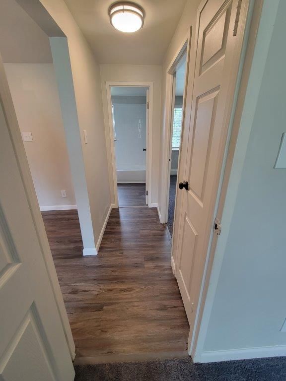 A hallway with hardwood floors and white doors leading to a bathroom.