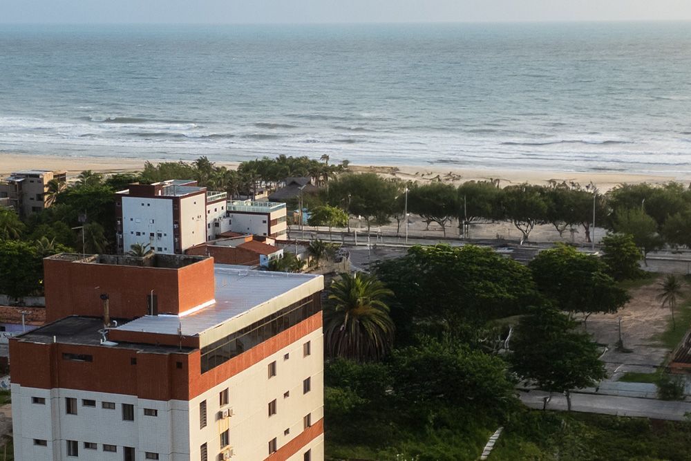 Uma praia com mesas, cadeiras e guarda-sóis de palha-Boreas-Apart-Hotel