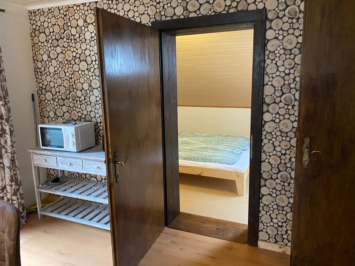 Een kamer met een magnetron en een deur die naar een slaapkamer leidt.