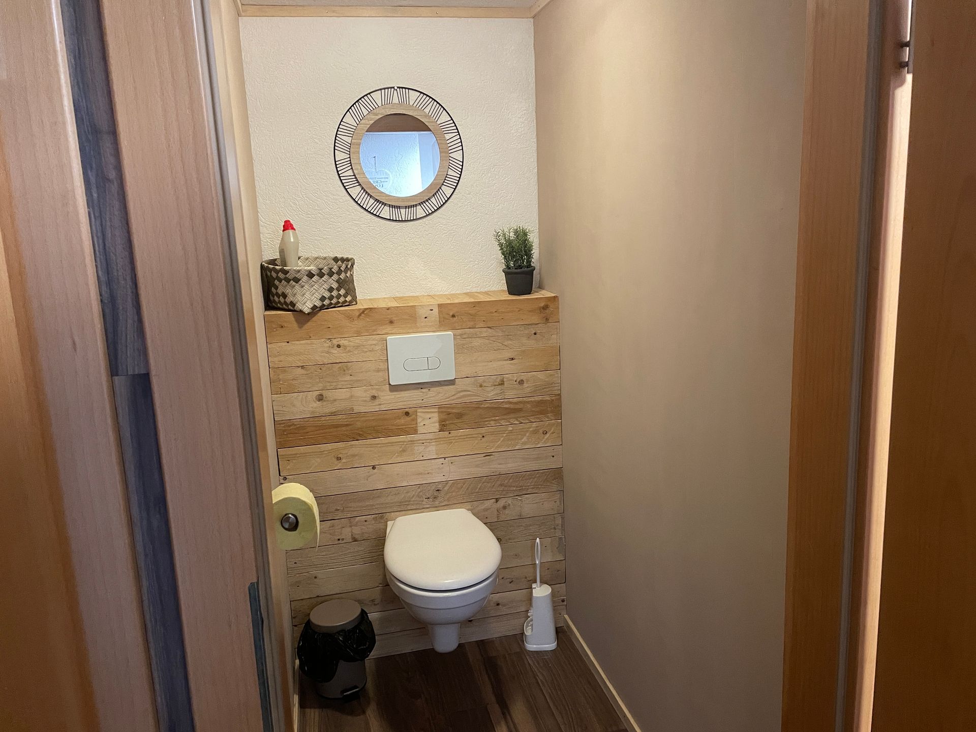 Een badkamer met een toilet en een spiegel aan de wand.