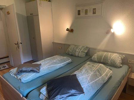 Twee bedden met blauwe lakens en kussens in een slaapkamer.