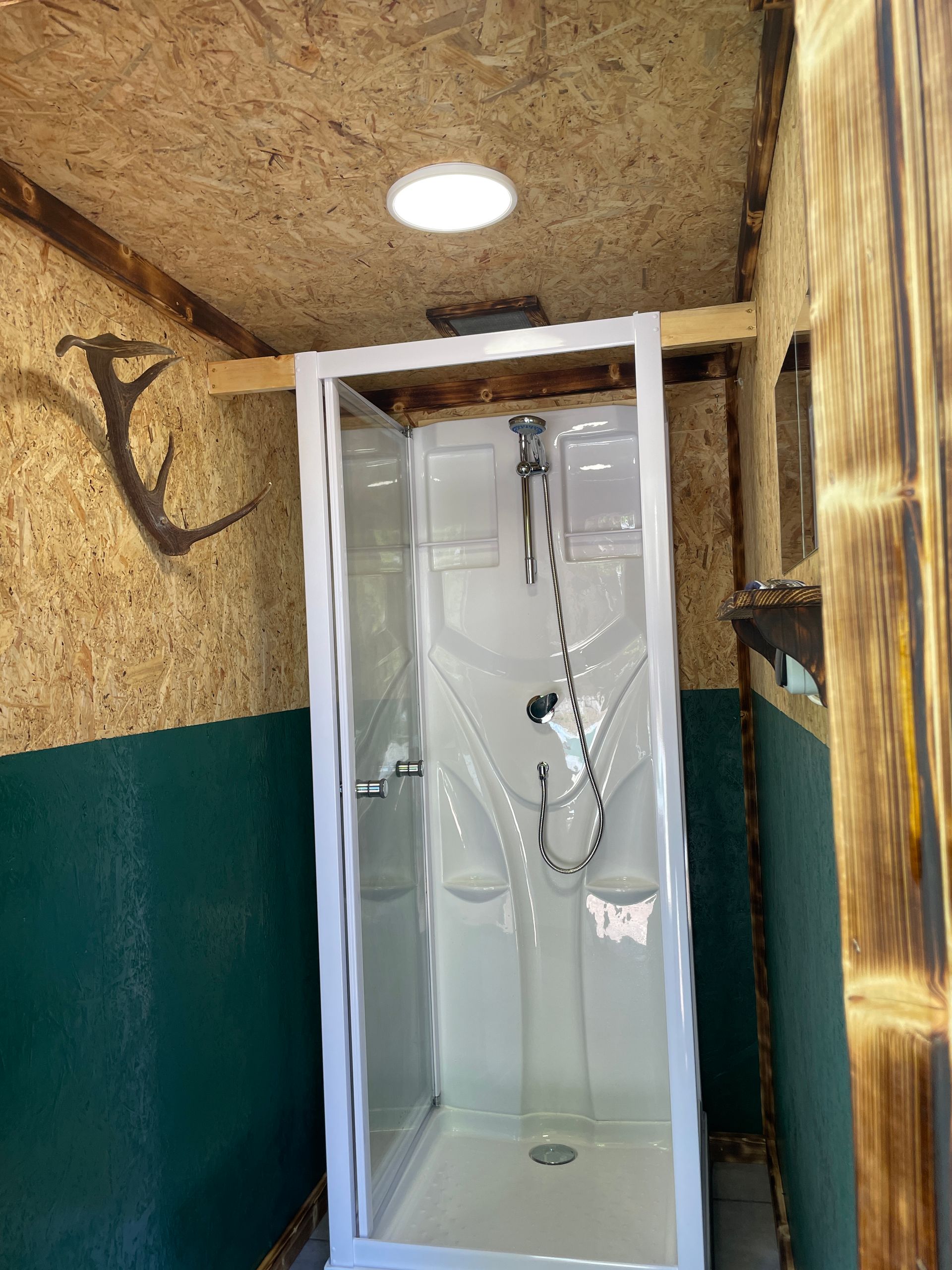 Een douchecabine in een badkamer met een lamp aan het plafond.