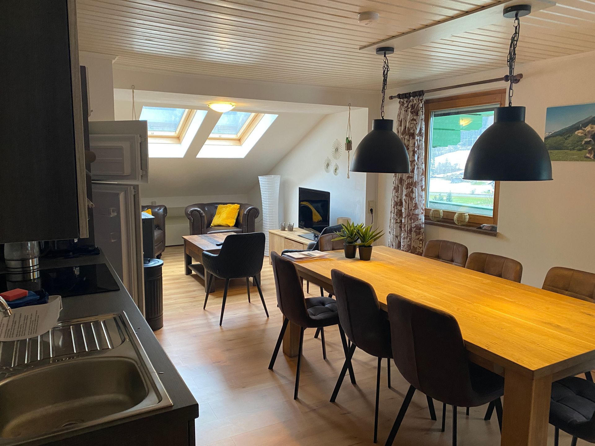 Een keuken met een eettafel, stoelen en een spoelbak.