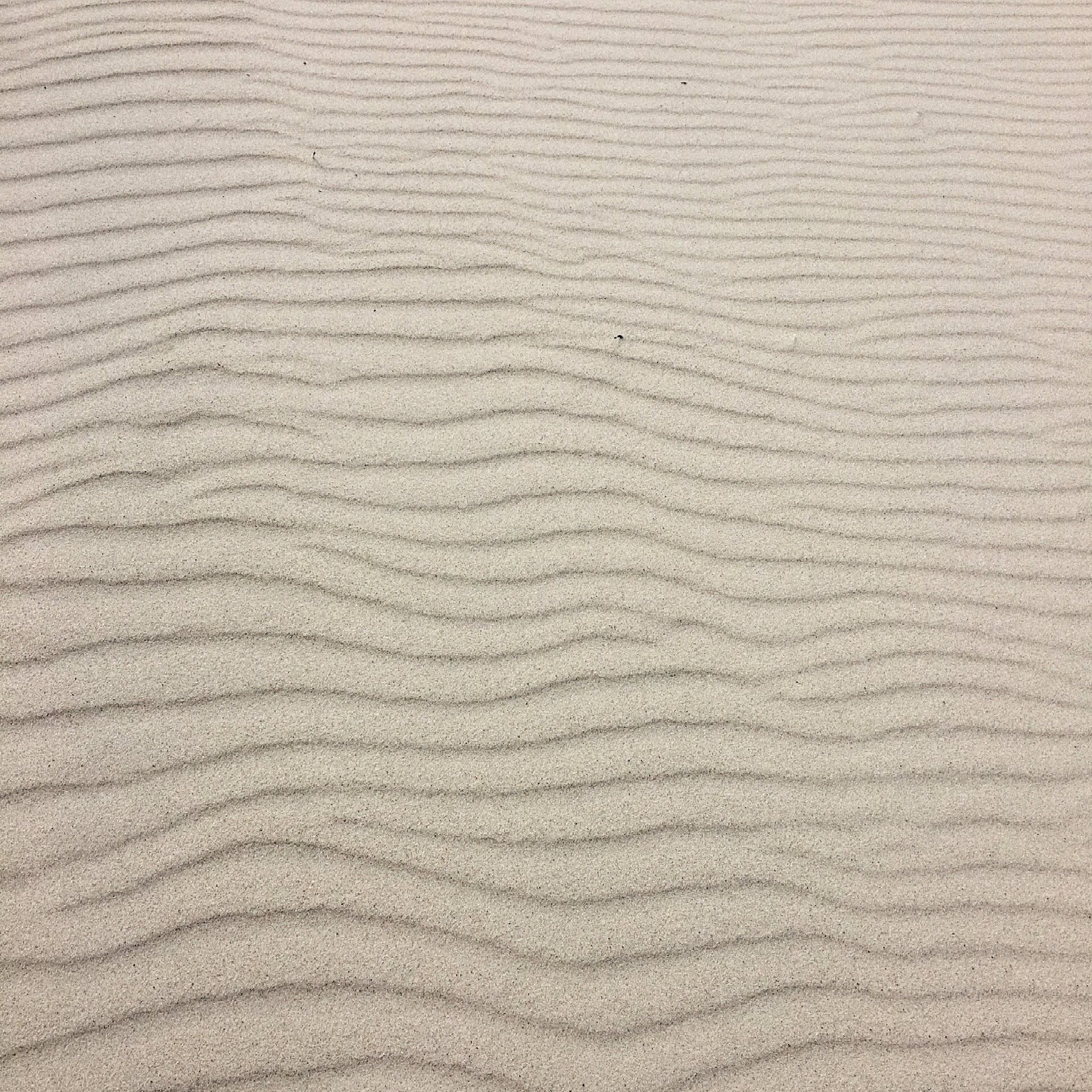 Een close-up van een zandstrand met golven in het zand.