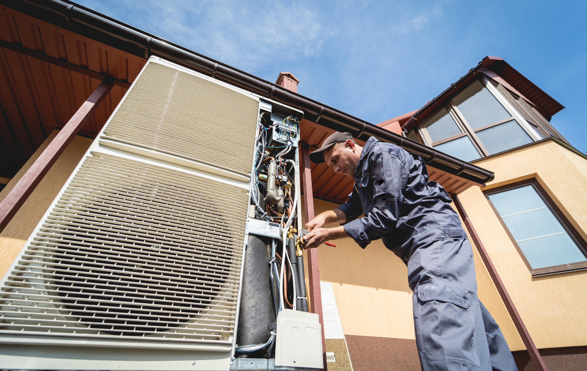 A man is working on an air conditioner outside of a house.