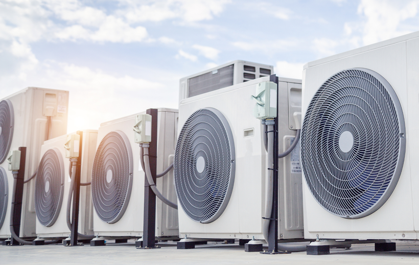 A row of air conditioners are lined up in a parking lot.