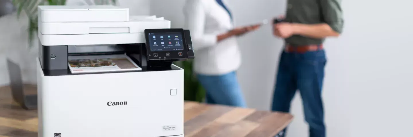 A man and a woman are standing next to a printer.