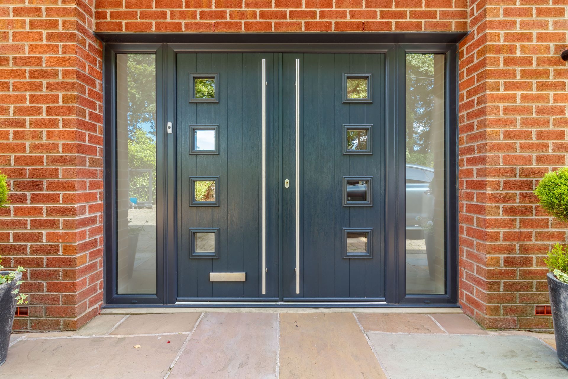The front of a brick house with a black  pair of composite style doors