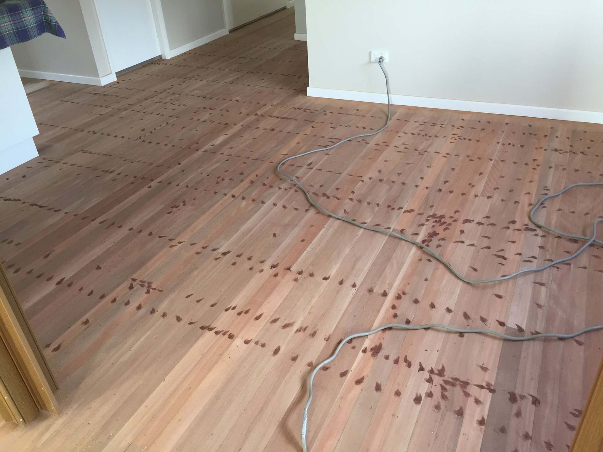 A Wooden Floor With A Cord Laying On It In A Room — Brett Hall Floorsanding in Kempsey, NSW