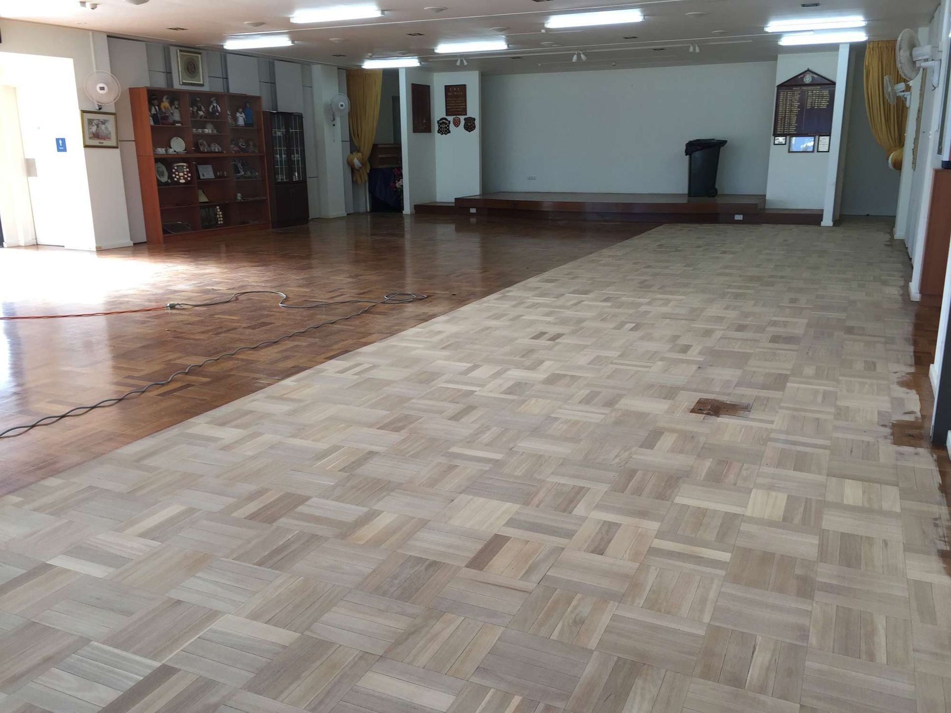A Large Empty Room With A Wooden Floor — Brett Hall Floorsanding in Laurieton, NSW