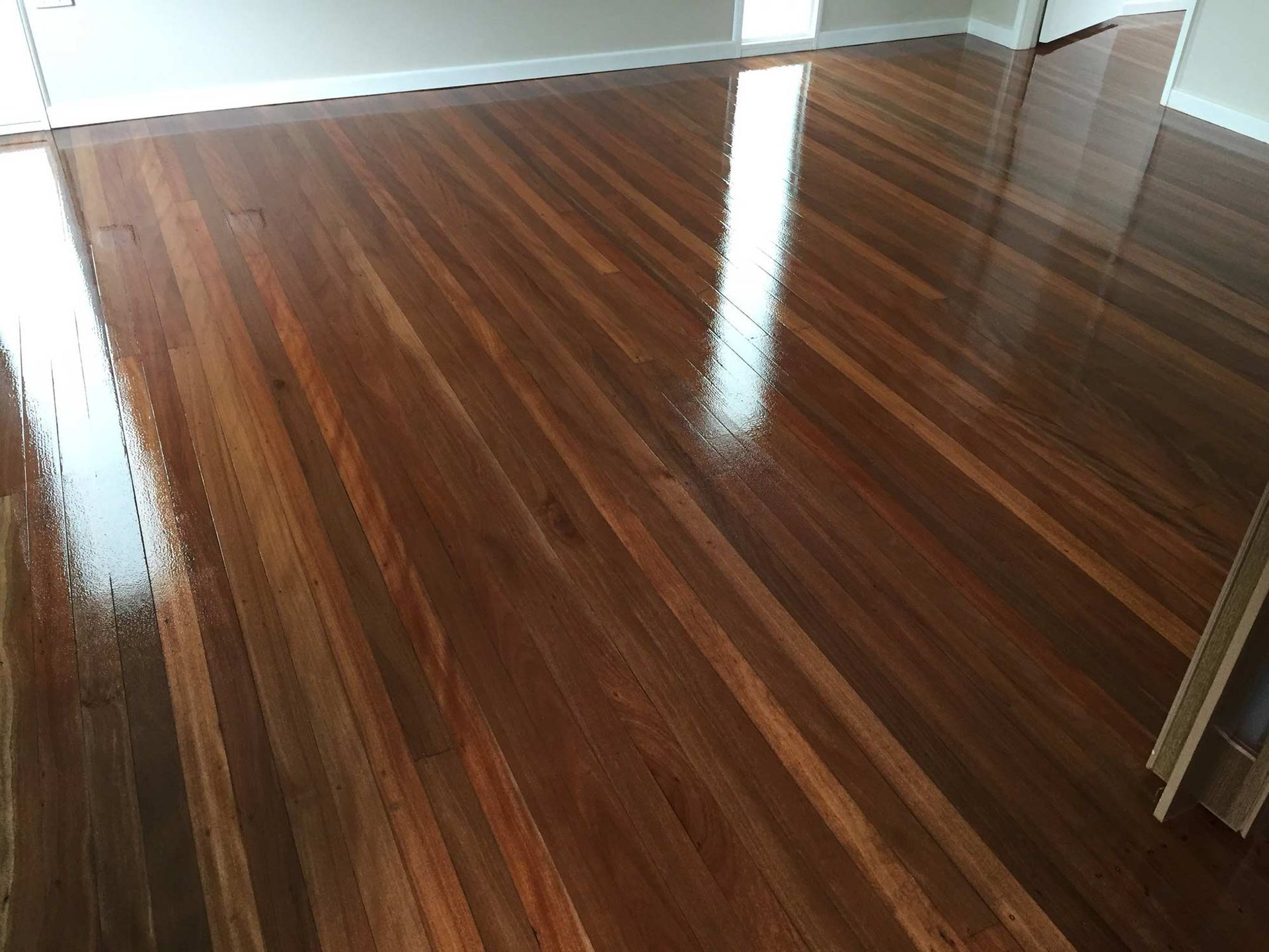 A Living Room With A Wooden Floor And A Door — Brett Hall Floorsanding in Kempsey, NSW