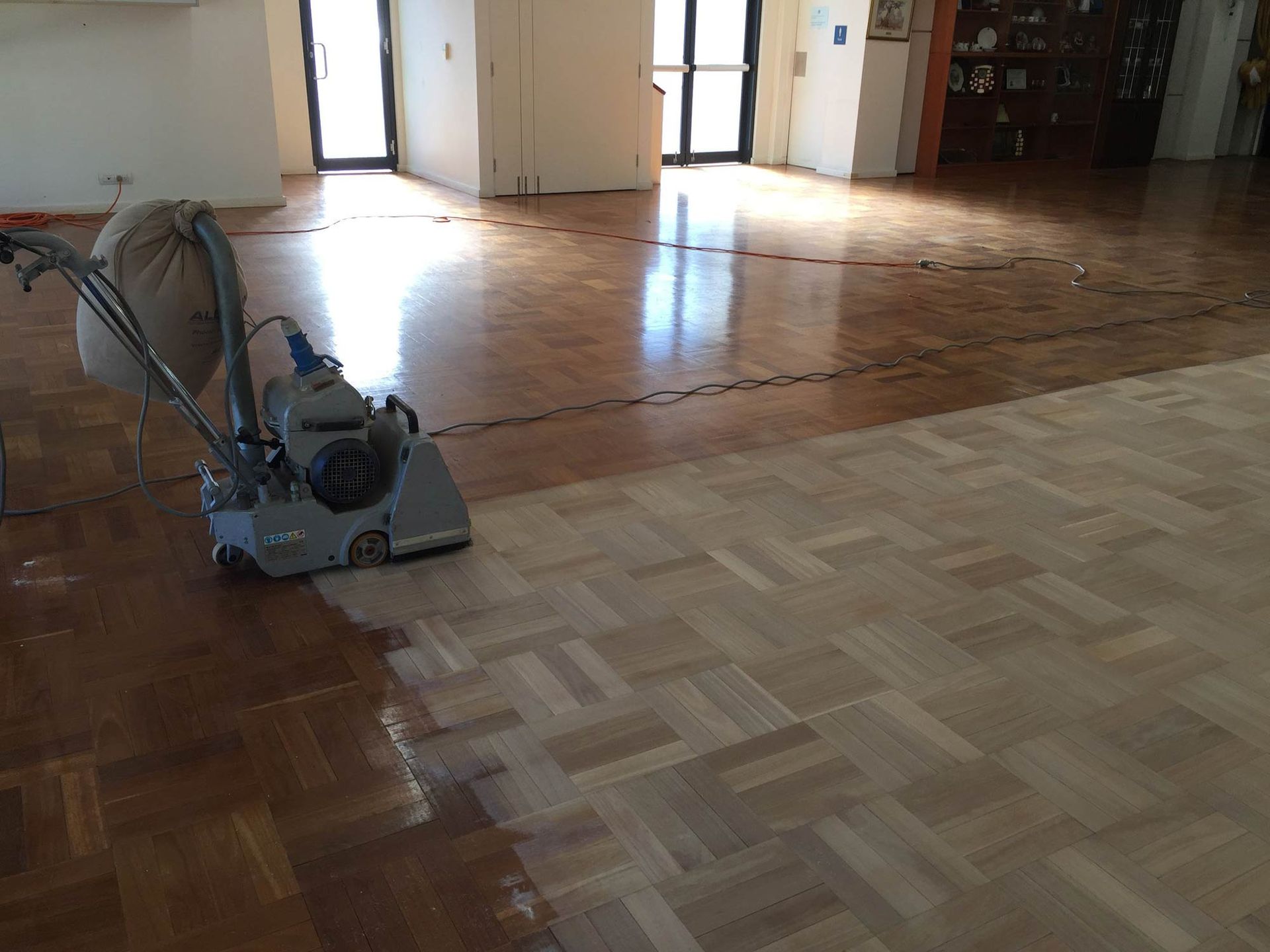 A Machine Is Sanding A Wooden Floor In A Room — Brett Hall Floorsanding in Kempsey, NSW