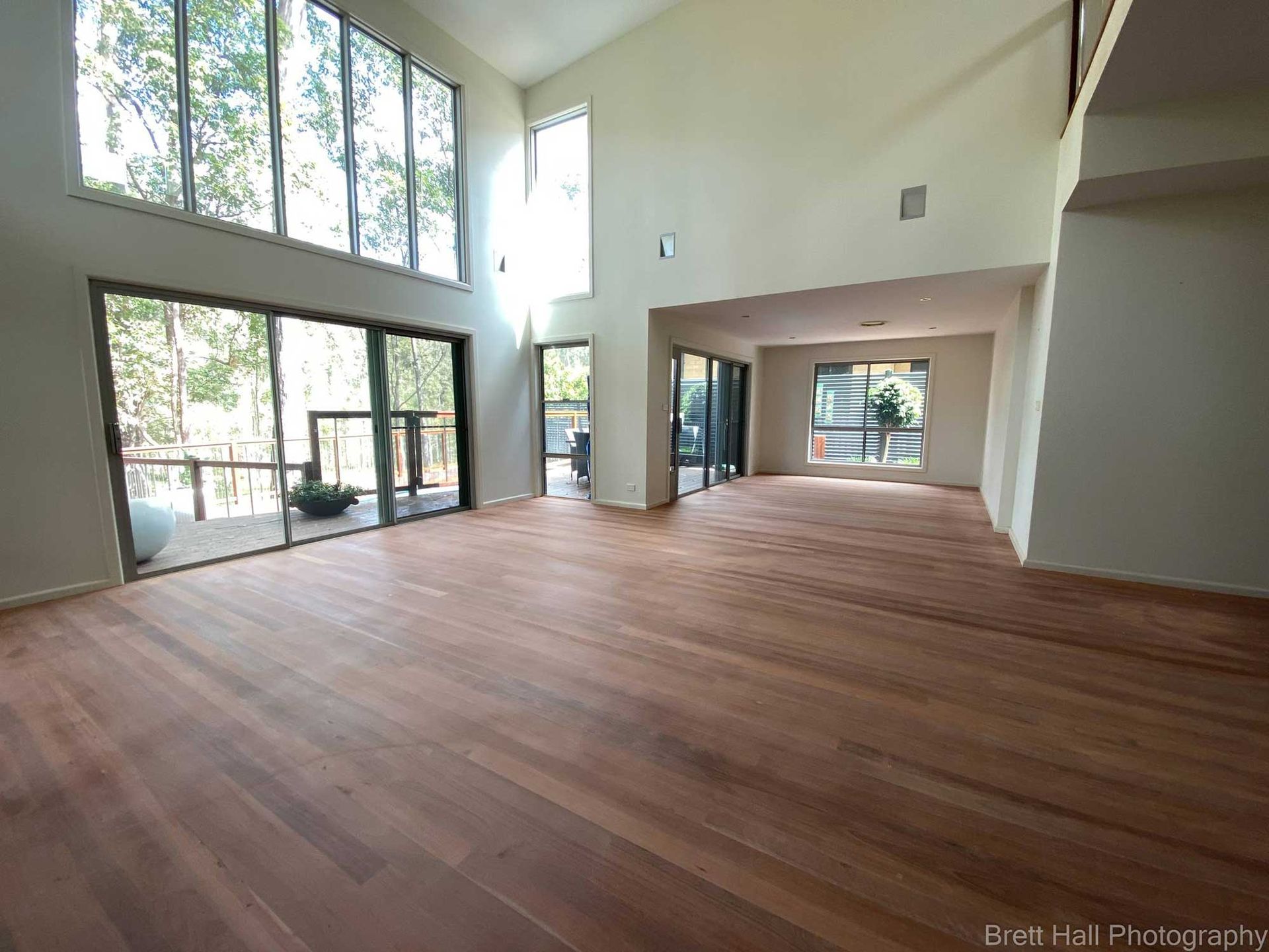 A Large Empty Room With Hardwood Floors And Lots Of Windows — Brett Hall Floorsanding in Port Macquarie, NSW