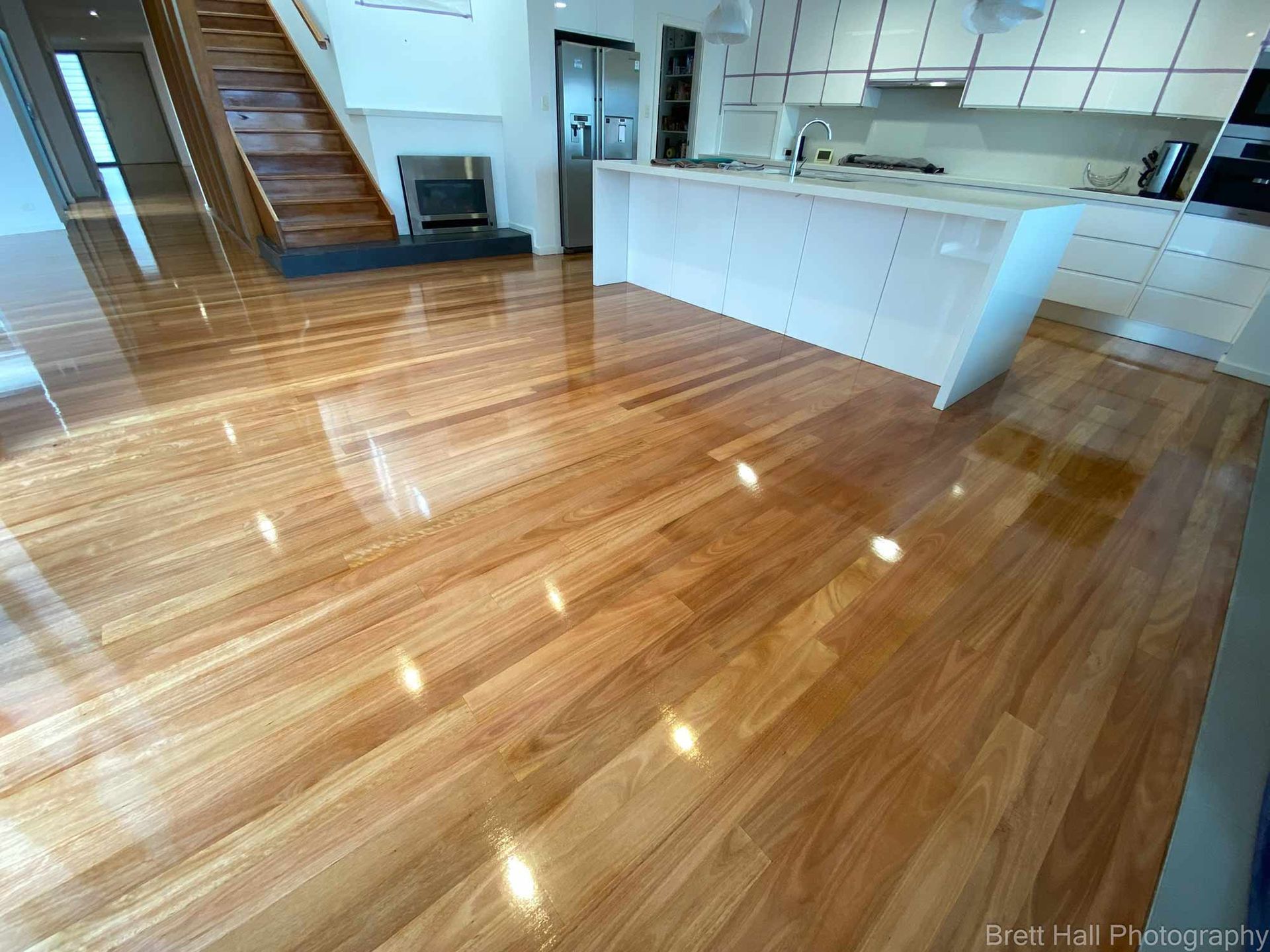 A Kitchen With A Wooden Floor And White Cabinets — Brett Hall Floorsanding in Port Macquarie, NSW