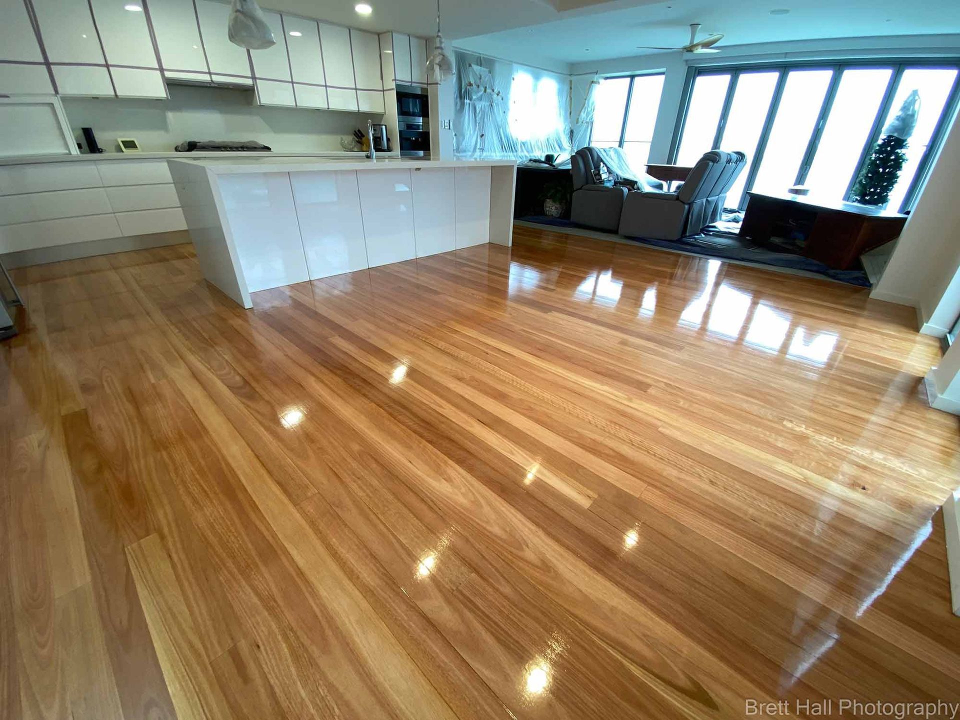 A Kitchen With A Wooden Floor And White Cabinets — Brett Hall Floorsanding in Port Macquarie, NSW