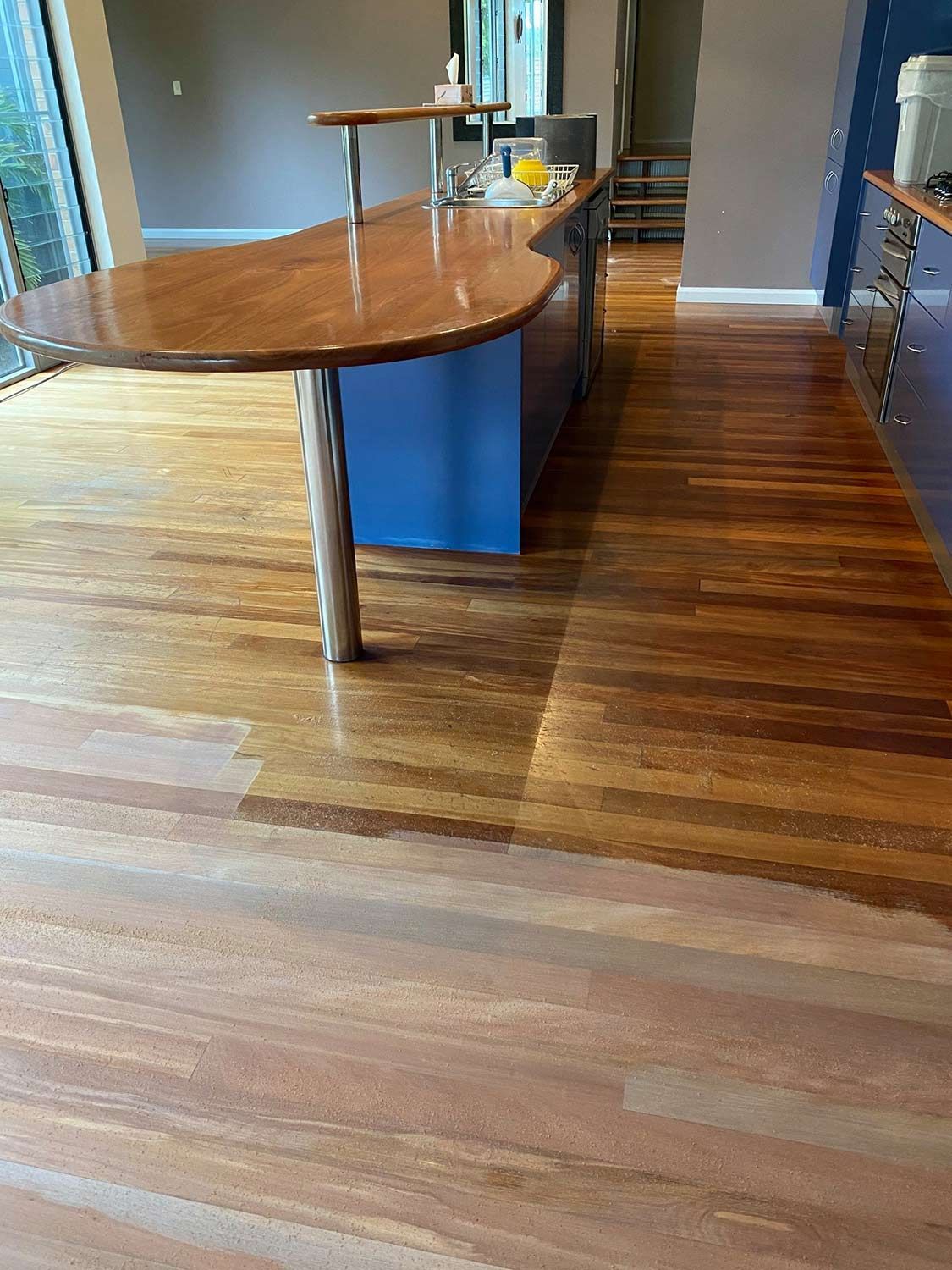 A Kitchen With A Wooden Floor And A Blue Island — Brett Hall Floorsanding in Wauchope, NSW