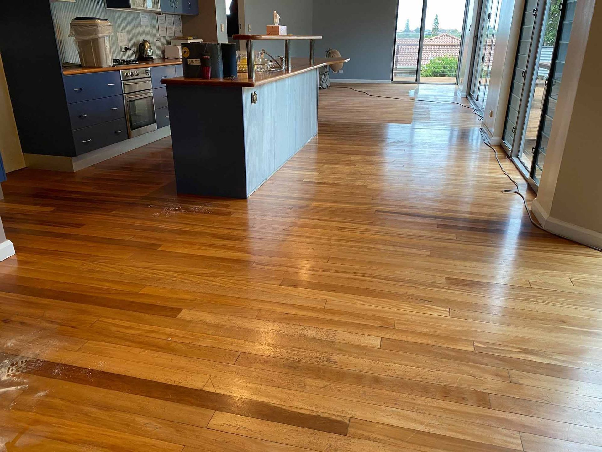 A Kitchen With A Wooden Floor And A Large Island — Brett Hall Floorsanding in Wauchope, NSW