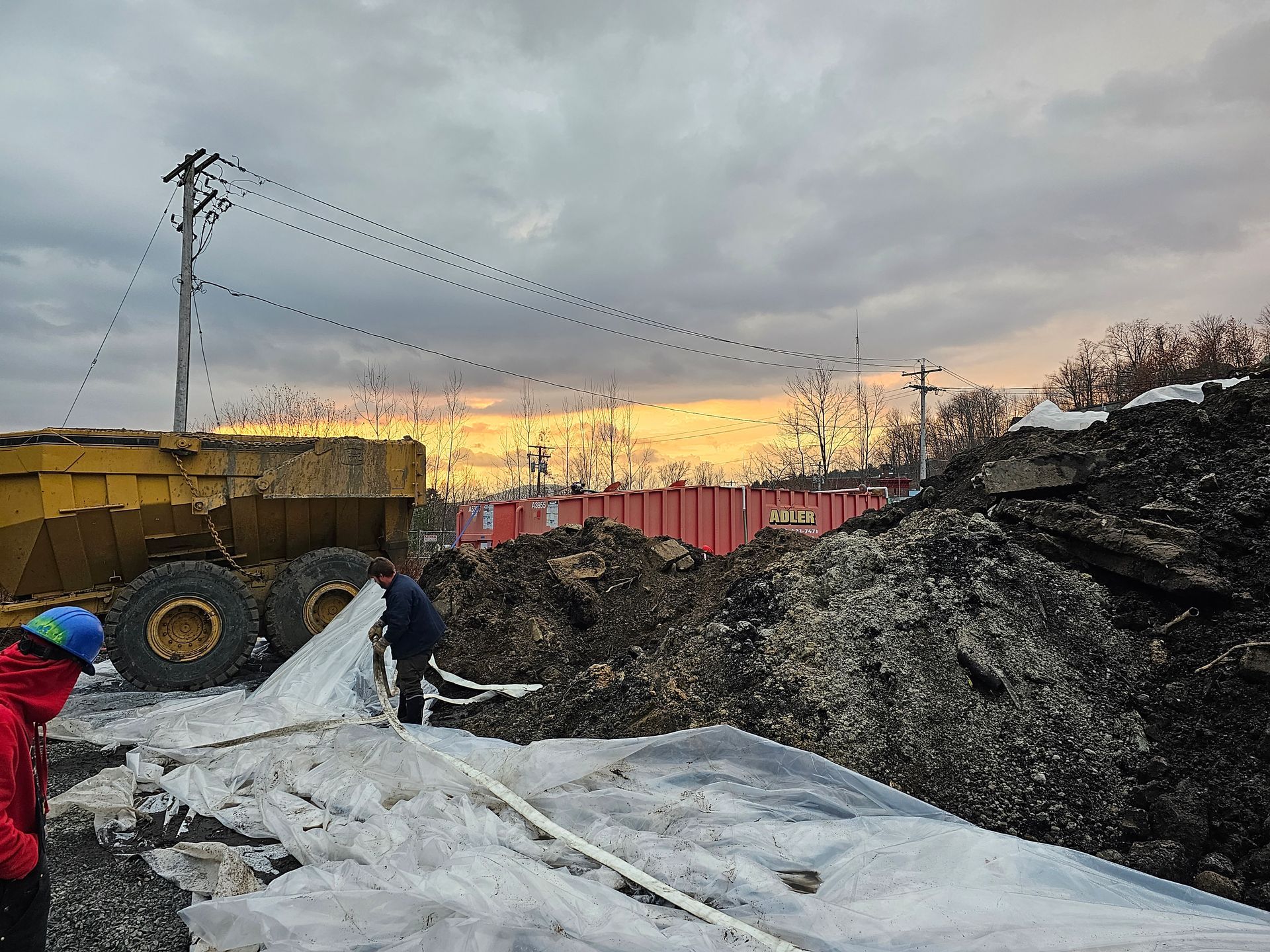 Heavy construction equipment from MP is loading a pile of waste into a dump truck. 