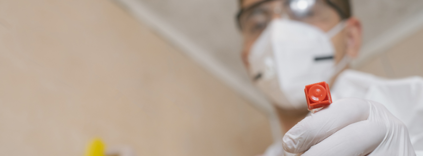 A close up of a person wearing a mask and gloves holding a spray bottle.