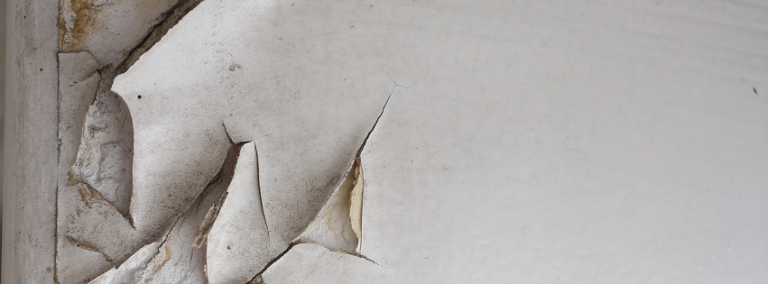 A close up of a white wall in a home with peeling, white lead paint.