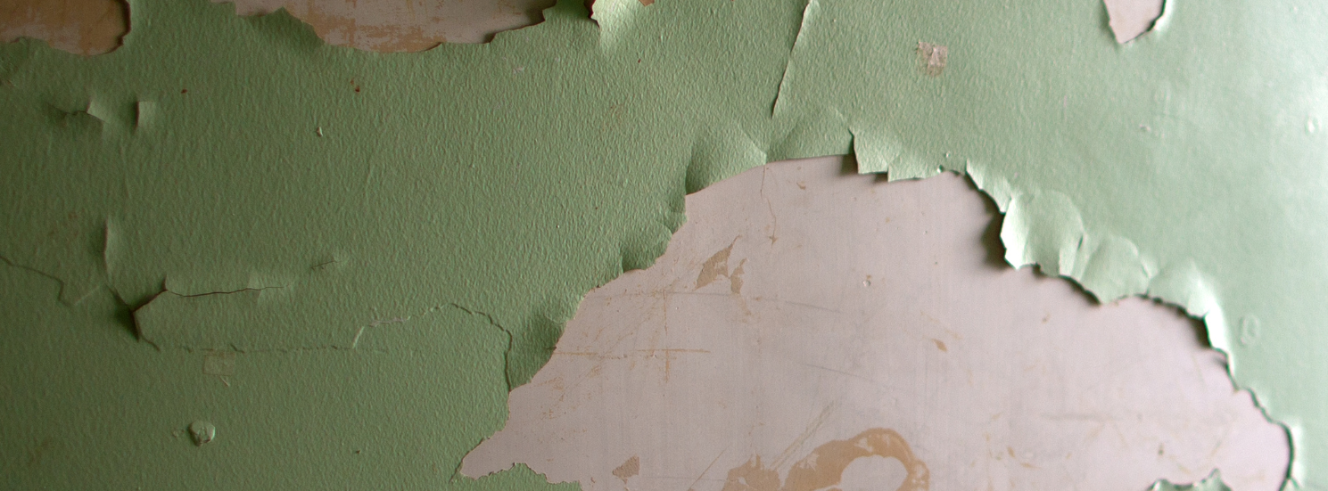 A close up of a  wall in a home with peeling lead paint.