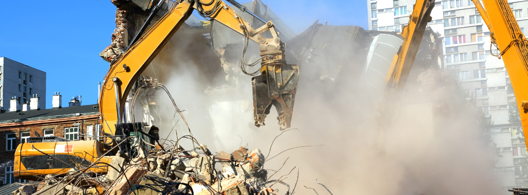 An MP Environmental Services excavator is demolishing a building.