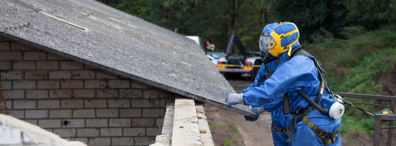 An MP Environmental Services employee is cutting a piece of asbestos from the roof of a building.