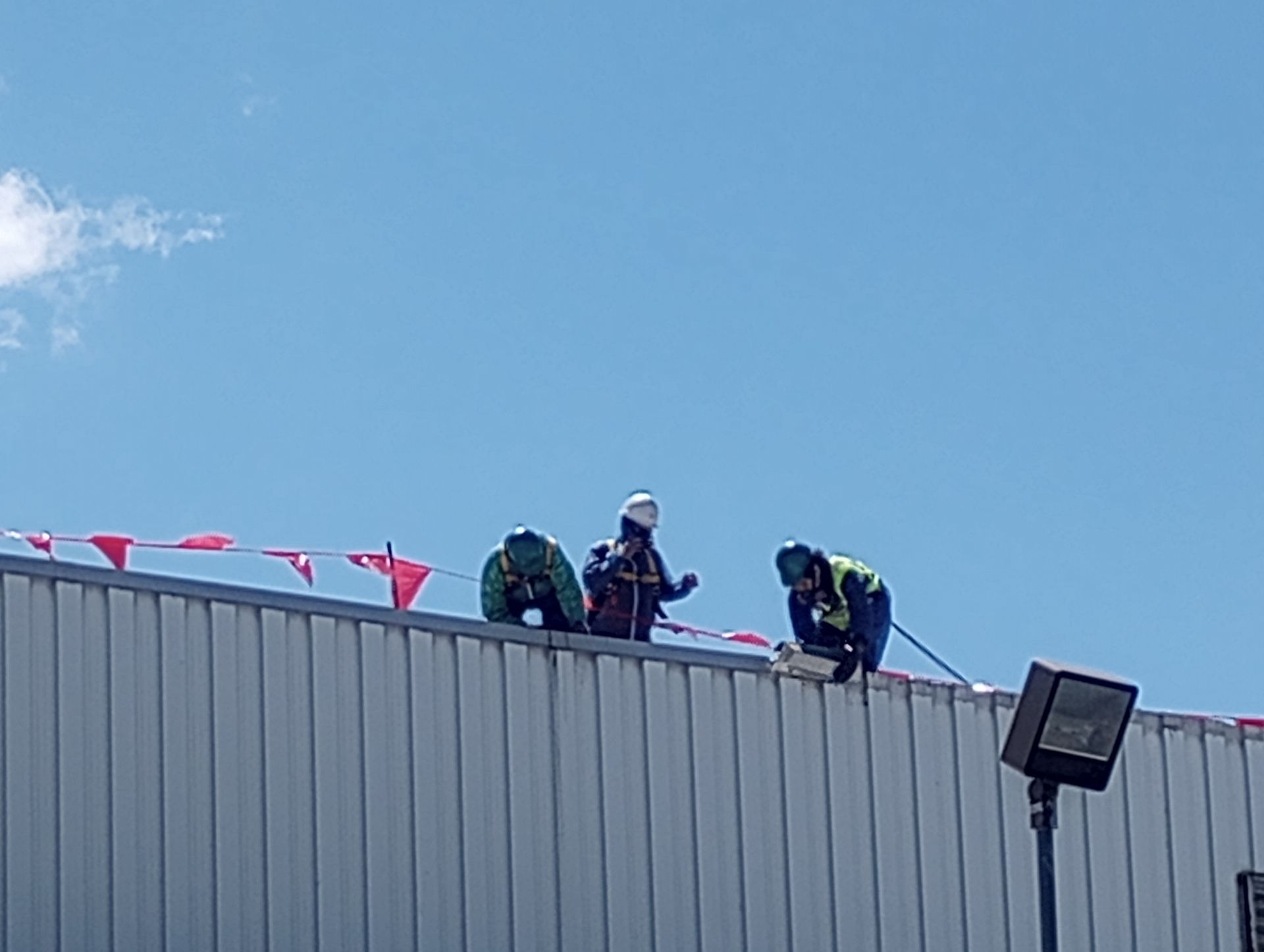 A group of MP Environmental employees are working on the roof of a  commercial building.