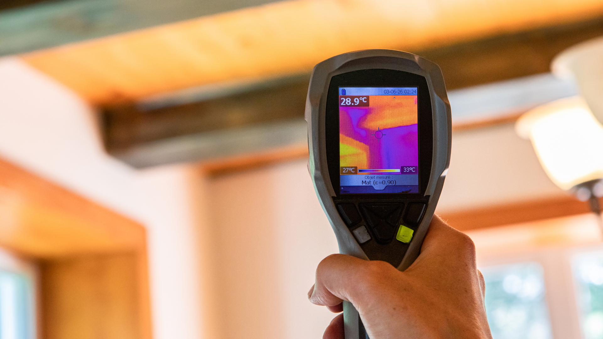 A person is holding a thermal camera in their hand to test air quality in a home. 