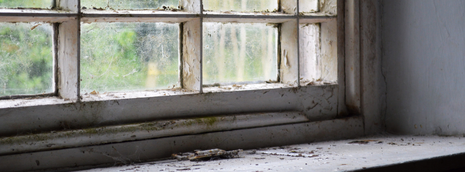 An old window with a dirty sill and chipped paint.