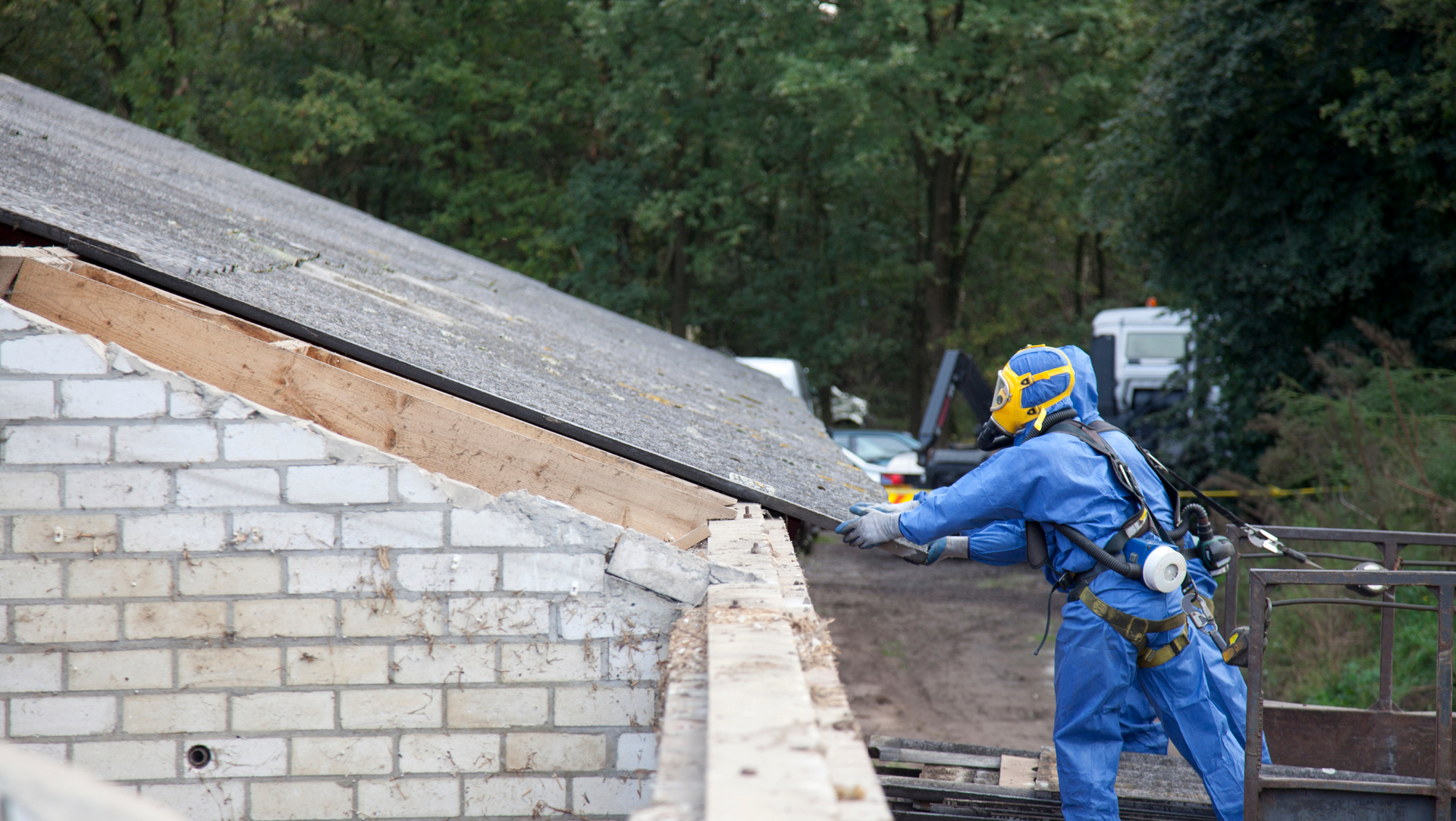 An MP Environmental employee in a protective suit is working on a roof.