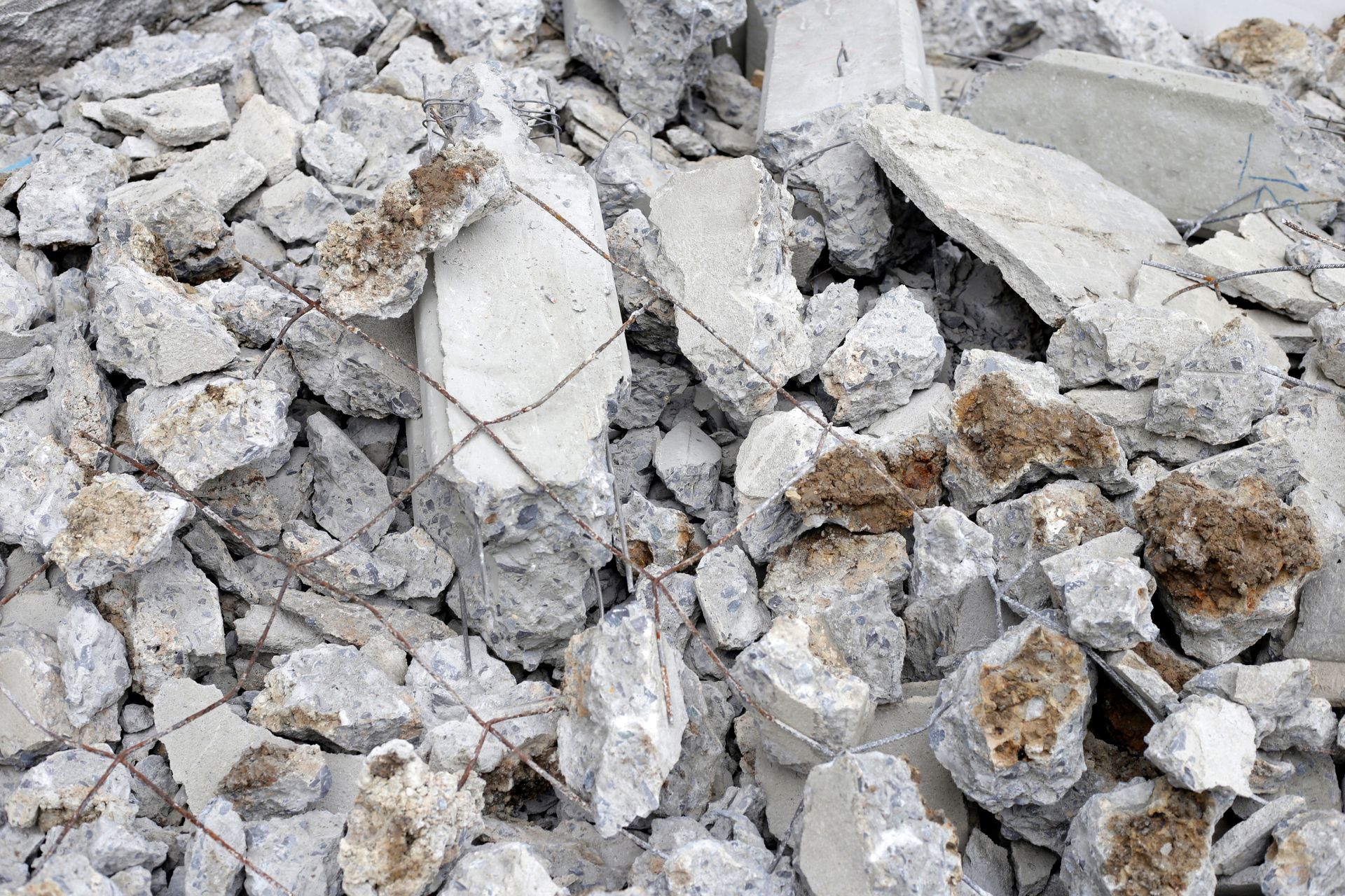 Pile of broken concrete with exposed rebar and brown staining.