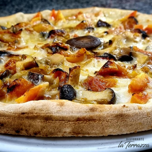 Pizza con verdure e formaggio, primo piano. Crosta marrone chiaro, condimenti arancioni e neri.