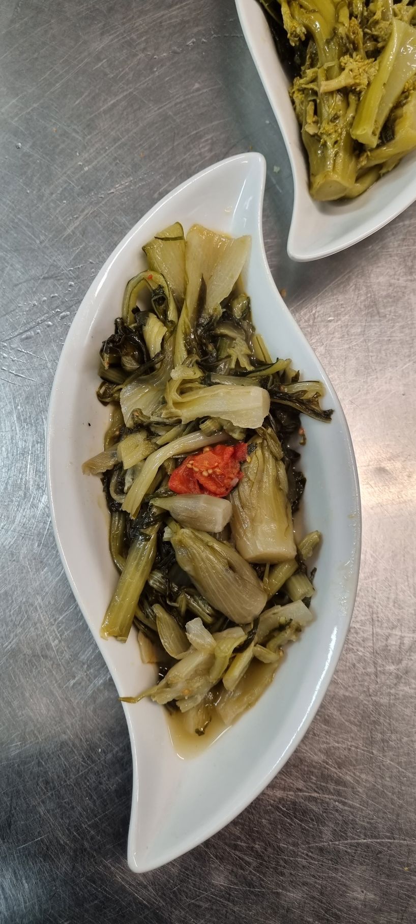 Due piatti bianchi a forma di foglia con verdure verdi cotte