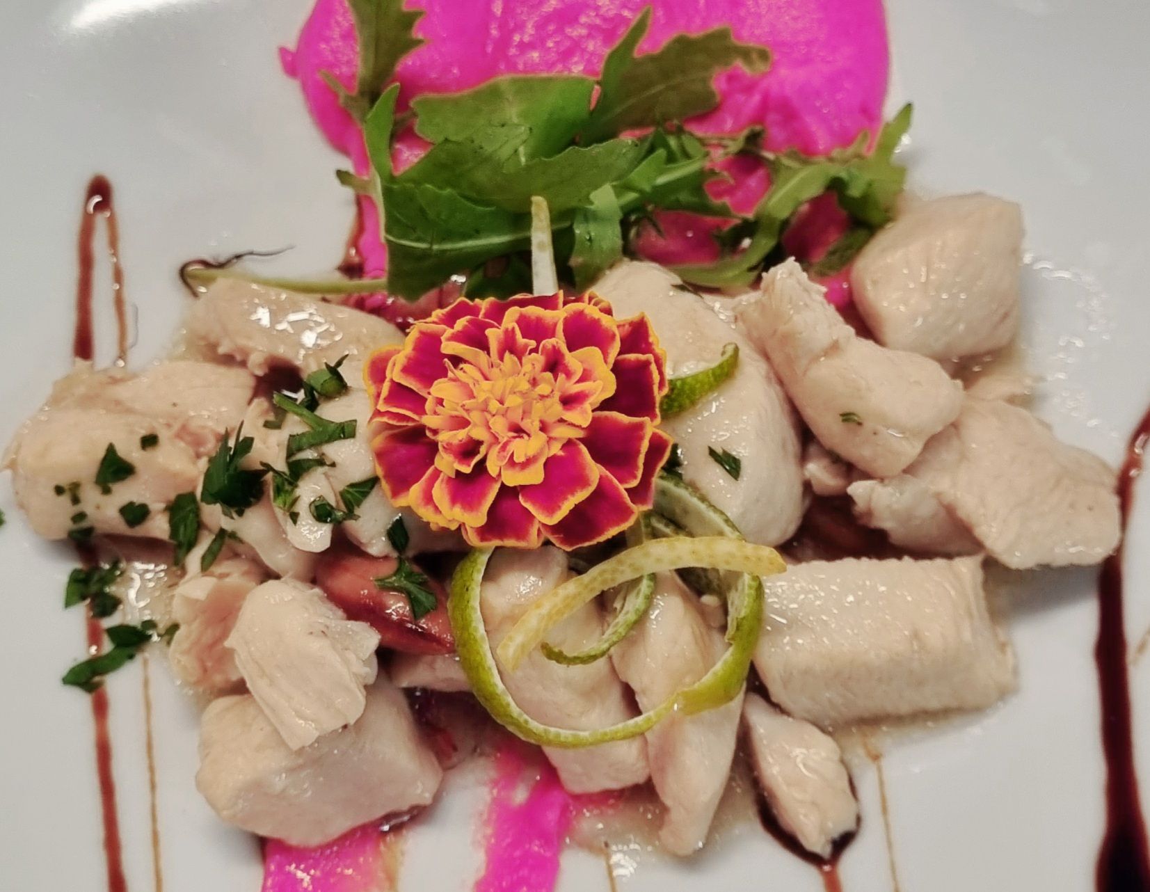 Insalata di pollo con barbabietole sottaceto, rucola e fiori commestibili, condita con salsa.
