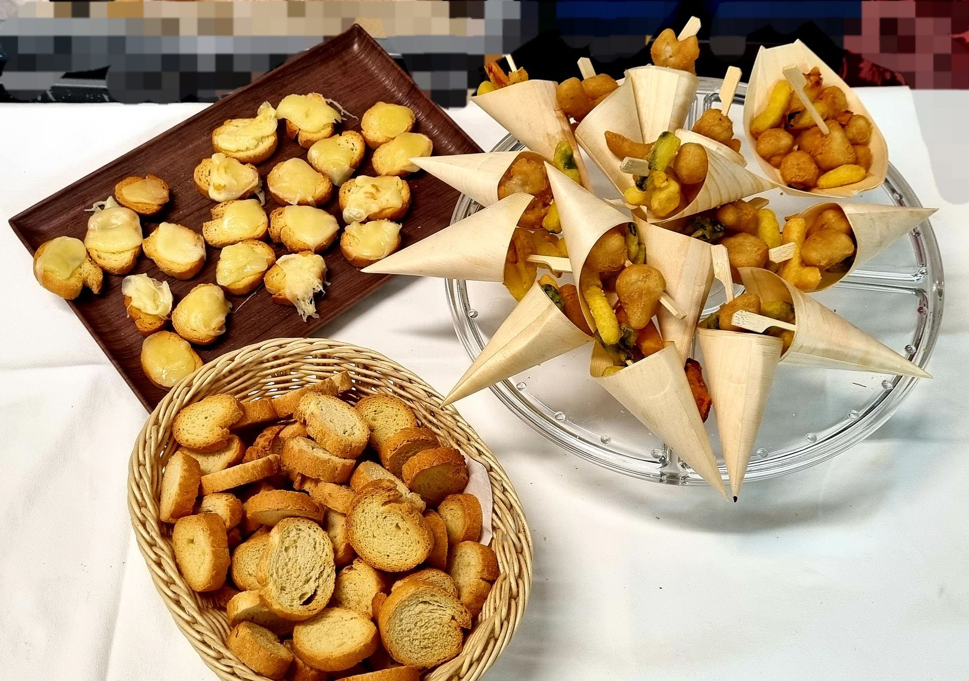 Assortimento di antipasti: stuzzichini fritti in coni di carta, cracker cotti al forno in un cestino e pane tostato
