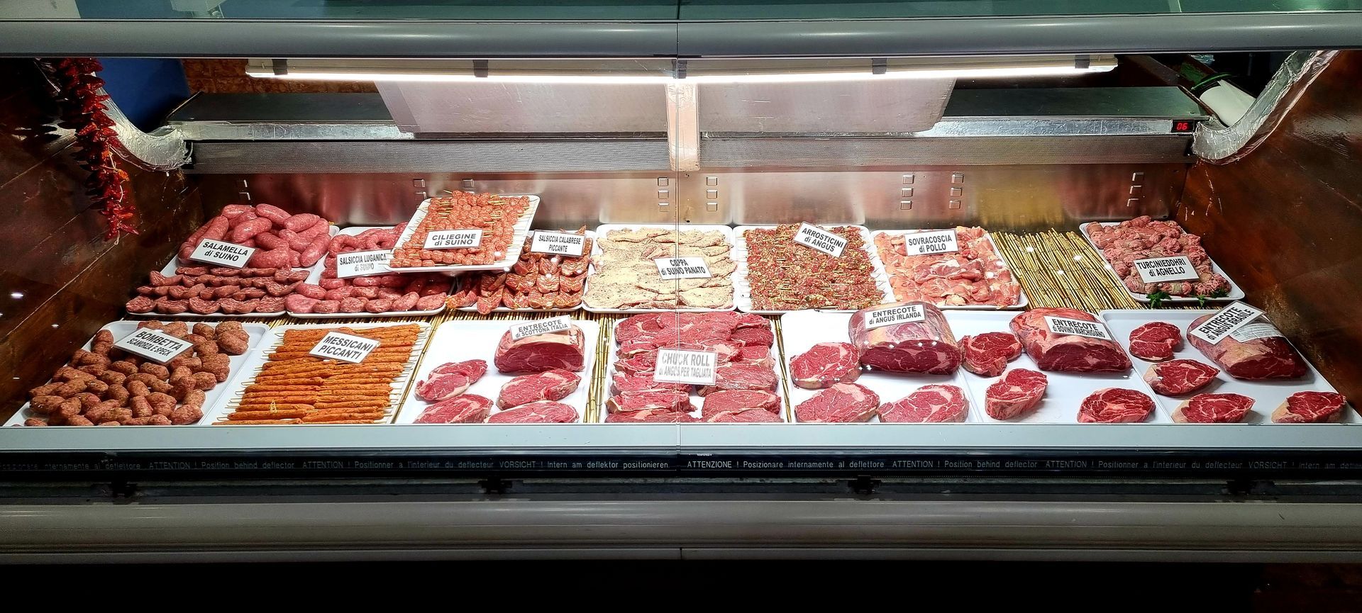 Vetrina espositiva con vari tagli di carne cruda, illuminata da luci soffuse.