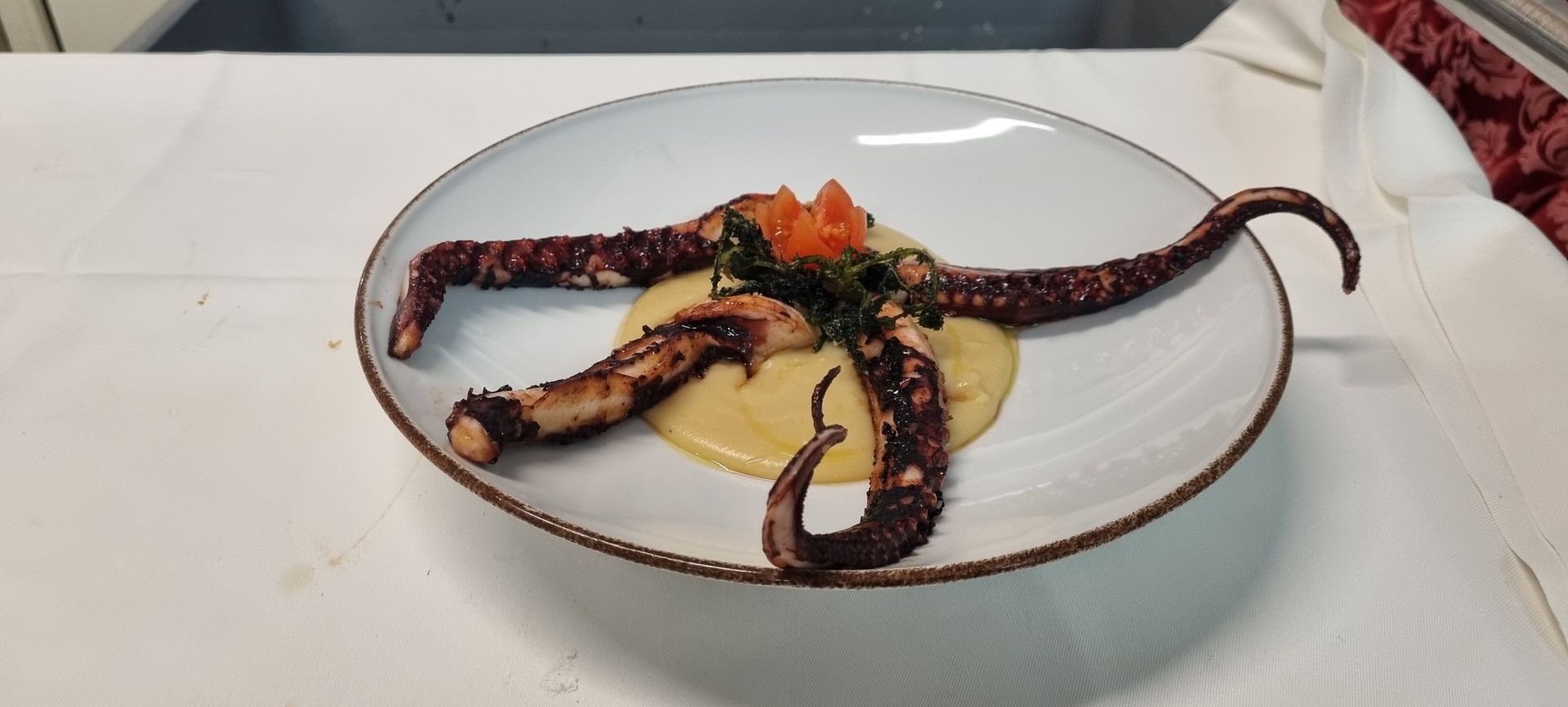 Polpo alla griglia con salsa cremosa su un piatto.